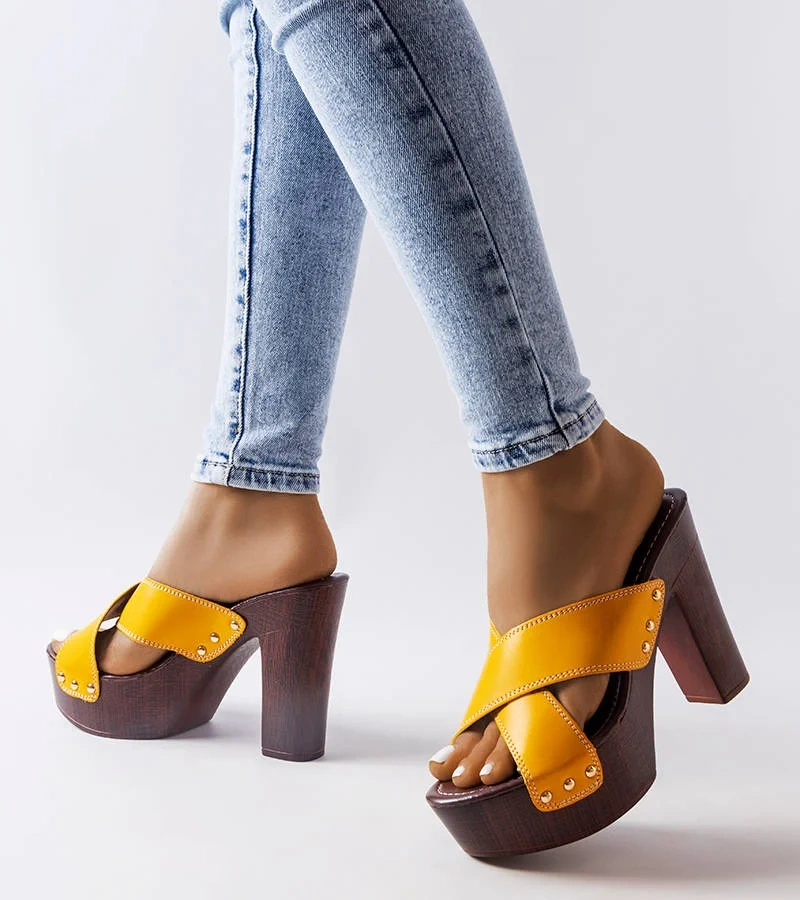 Żółte klapki typu drewniaki na wysokim słupku