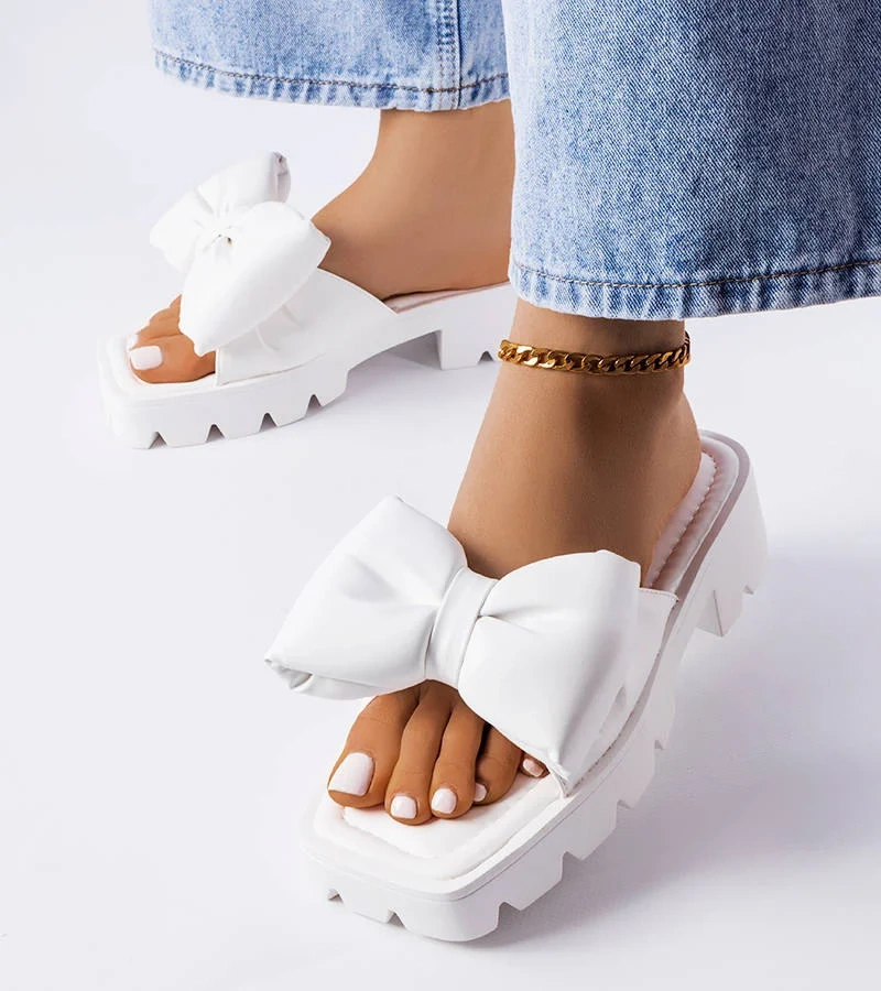 Białe klapki zdobione kokardą na masywnej podeszwie