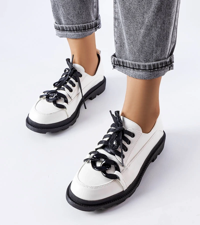 Białe półbuty z czarną podeszwą i łańcuchem